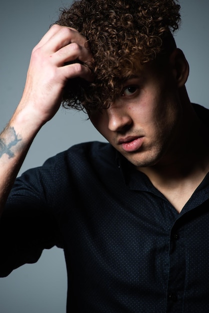 Un homme aux cheveux bouclés et une croix bleue sur la tête