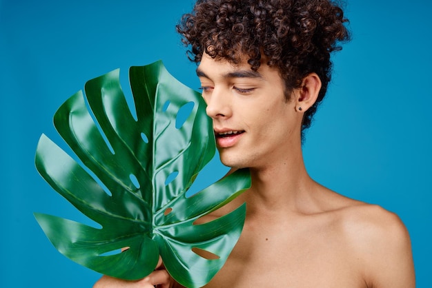 Homme aux cheveux bouclés épaules nues feuilles vertes écologie