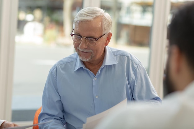 Homme aux cheveux gris attentif regardant des documents