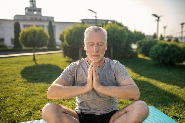 Homme Aux Cheveux Gris Pratiquant Le Yoga à L'extérieur, Les Mains En Namaste