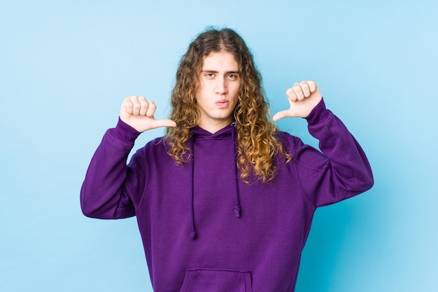 L'homme aux cheveux longs posant isolé se sent fier et confiant, exemple à suivre.