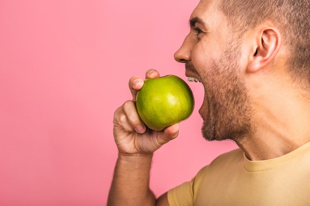 Homme aux dents blanches parfaites et pomme verte. Montrant des dents et un sourire parfaits.