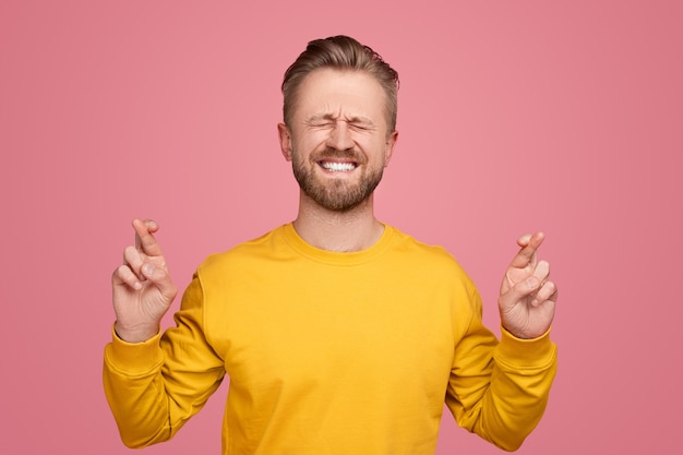 Homme aux doigts croisés sur fond rose