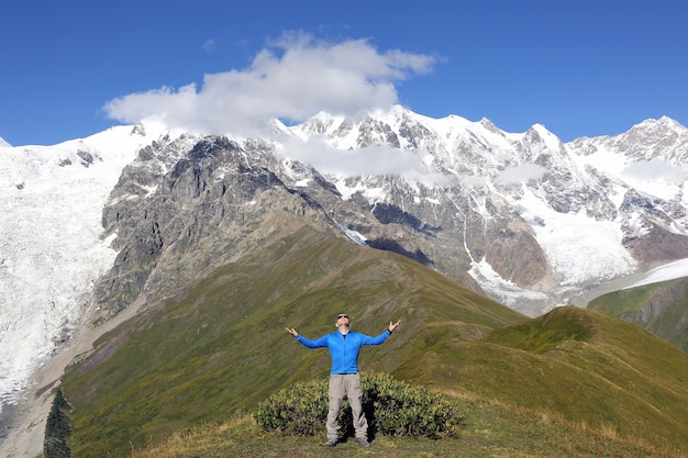 Homme aux mains levées debout sur les montagnes enneigées