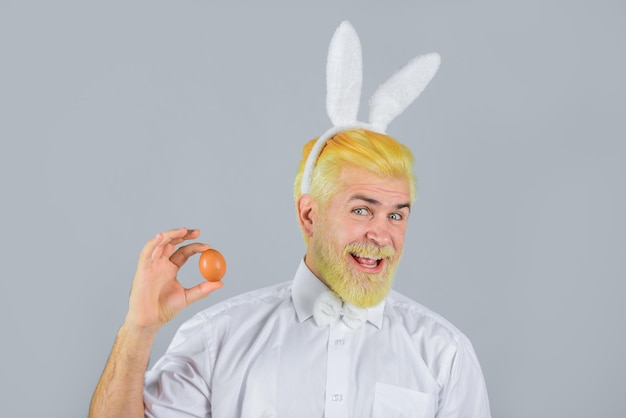 L'homme aux oreilles de lapin tient l'oeuf de pâques homme lapin l'homme aux oreilles de lapin tient l'oeuf de pâques au printemps