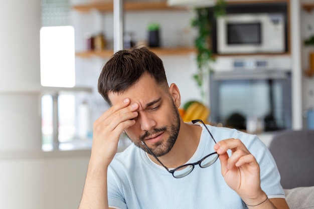 Homme aux yeux fatigués après un long travail tenant ses lunettes