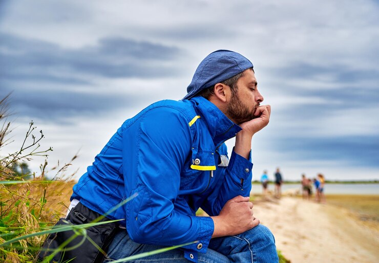 Photo un homme aux yeux fermés assis sur un champ contre le ciel