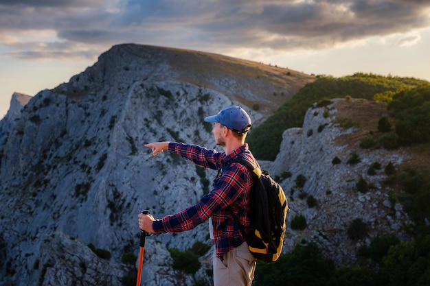 L'homme aventureux est au sommet de la montagne et profite de la belle vue pendant un coucher de soleil vibrant