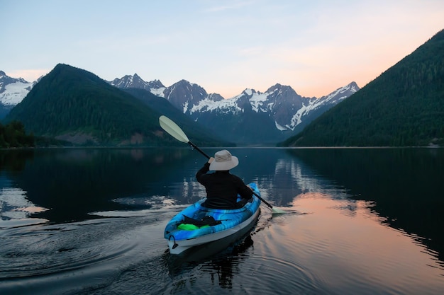 Homme aventureux faisant du kayak dans l'eau près du paysage de montagne canadien