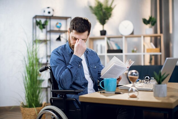 Homme ayant un besoin spécial se frottant les yeux en lisant un livre