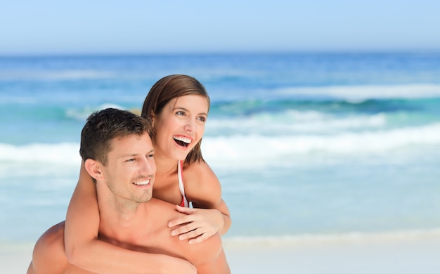 Homme ayant une femme un piggyback sur la plage