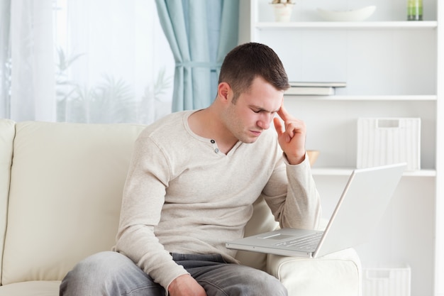 Homme ayant un mal de tête avec un ordinateur portable