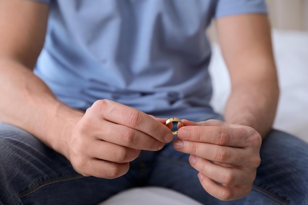 Homme avec bague de mariage assis sur le lit gros plan Concept de divorce