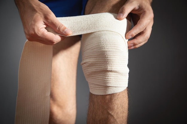 Homme bandant un genou blessé Concept de premiers secours et de médecine