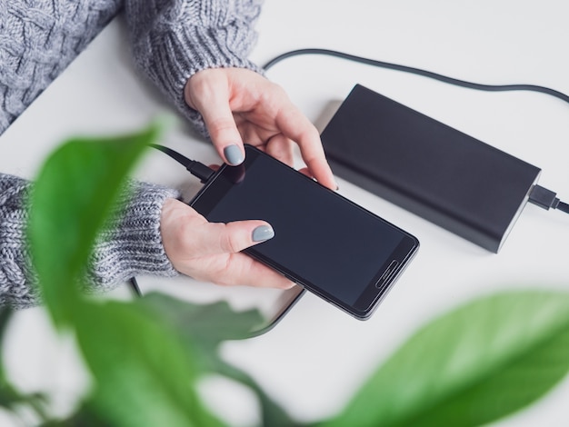 L'homme avec la banque d'alimentation charge le téléphone via un câble