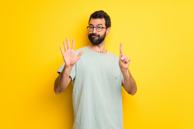 Homme à la barbe et chemise verte comptant six avec les doigts