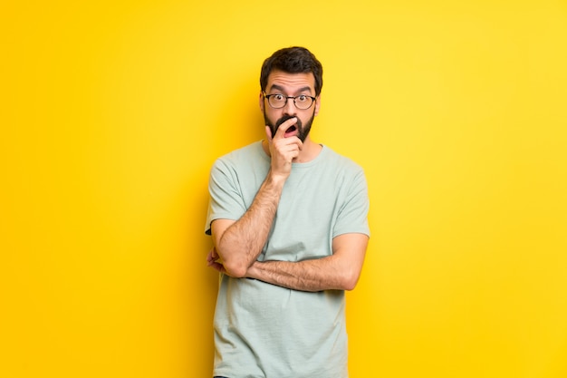 Homme à la barbe et à la chemise verte surpris et choqué en regardant à droite