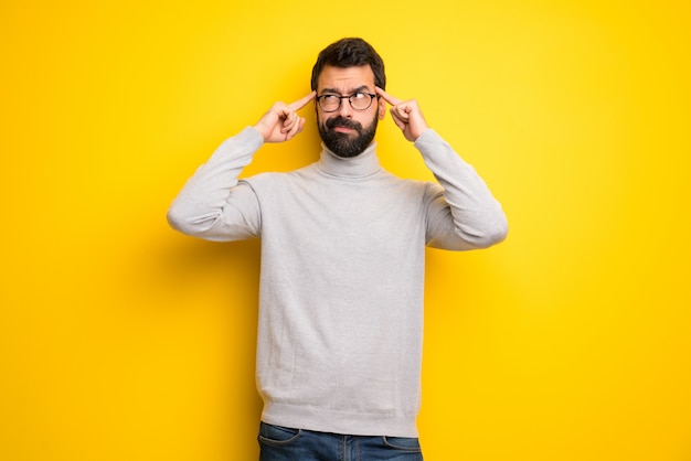 Homme avec barbe et col roulé ayant des doutes et penser