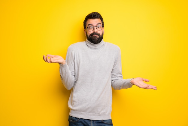 Homme avec barbe et col roulé ayant des doutes tout en levant les mains et les épaules