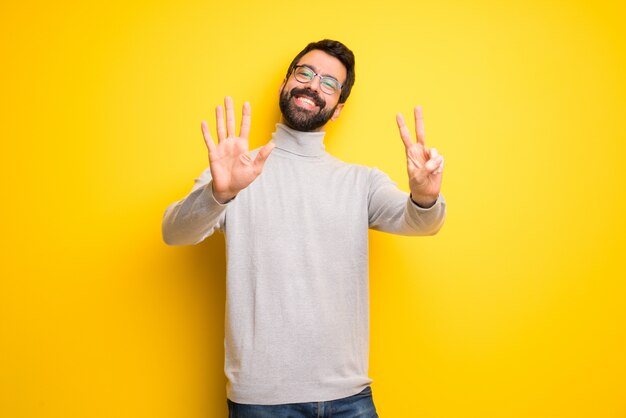 Homme à la barbe et col roulé comptant sept avec les doigts