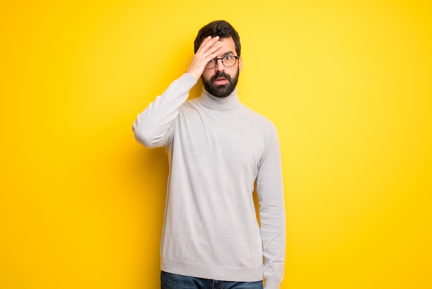 Homme à la barbe et col roulé avec surprise et expression faciale choquée