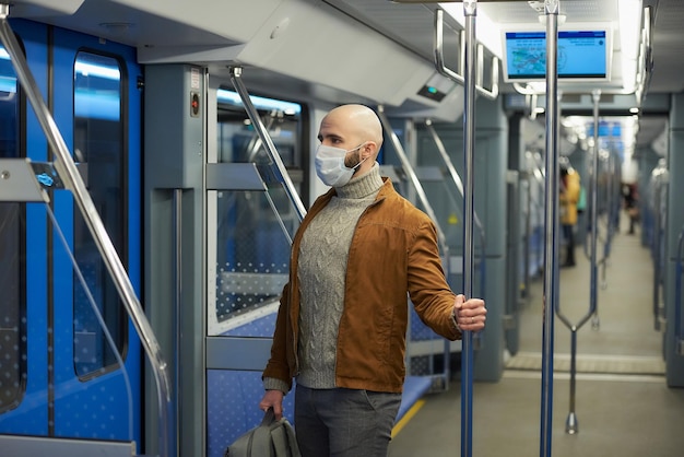 Un homme avec une barbe dans un masque médical pour éviter la propagation du coronavirus monte dans le métro