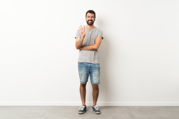 Homme à la barbe heureux et comptant quatre avec les doigts