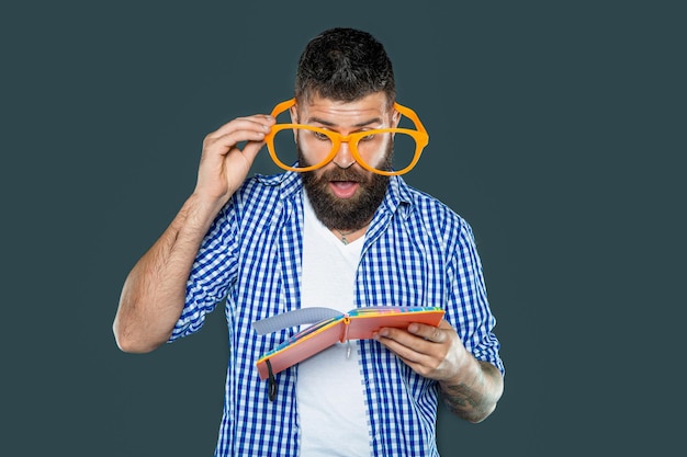 Un homme à la barbe avec des lunettes de fête a lu un livre.