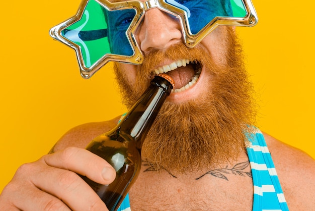 Homme avec barbe et lunettes de soleil boit de la bière