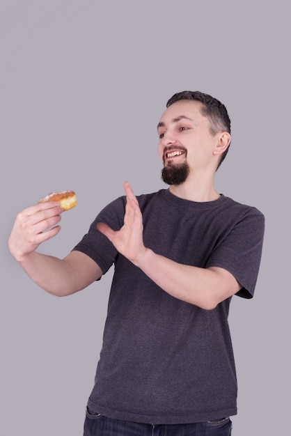 Homme à la barbe mangeant un chignon sur fond gris