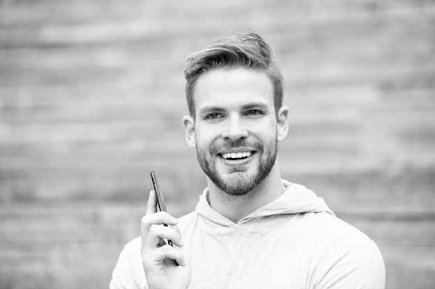 Homme à la barbe marche avec smartphone, fond urbain avec escaliers. L'homme à la barbe sur le visage souriant parle sur smartphone. Notion de communication. Guy heureux de répondre à l'appel sur smartphone.