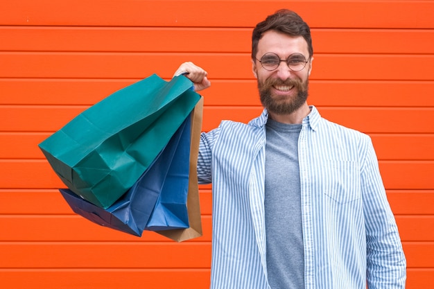 L'homme avec la barbe et la moustache tient des sacs à provisions