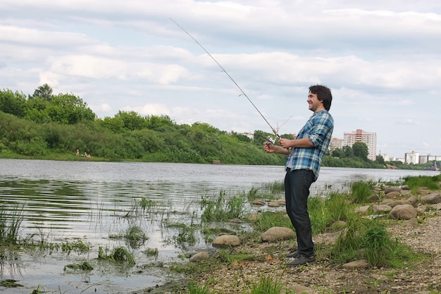 Un homme avec une barbe pêche pour filer dans la rivière