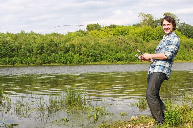 Un homme avec une barbe pêche pour filer dans la rivière