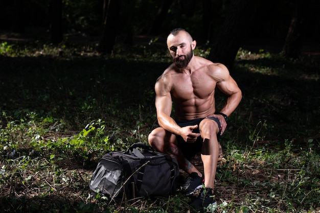 Homme barbe se reposant à l'extérieur dans le parc de la salle de sport