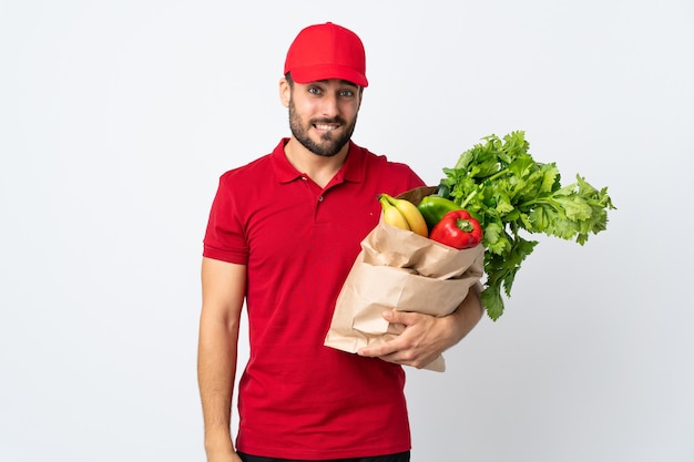 homme avec barbe tenant un sac plein de légumes