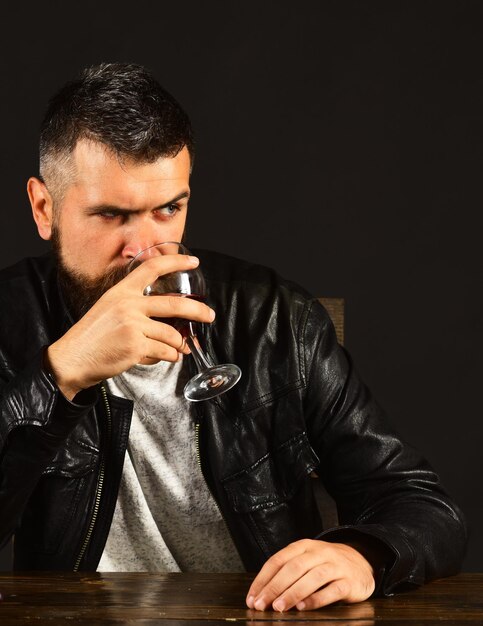 L'homme à la barbe tient un verre de vin sur fond marron