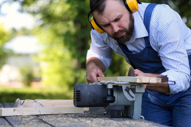 Homme de barbe travaillant sur la scie circulaire