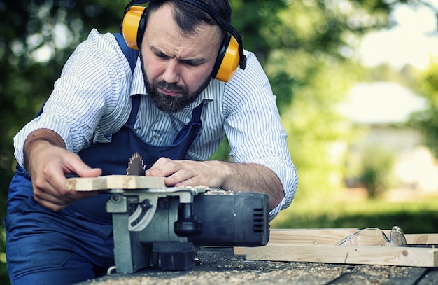 Homme de barbe de travailleur avec la scie circulaire