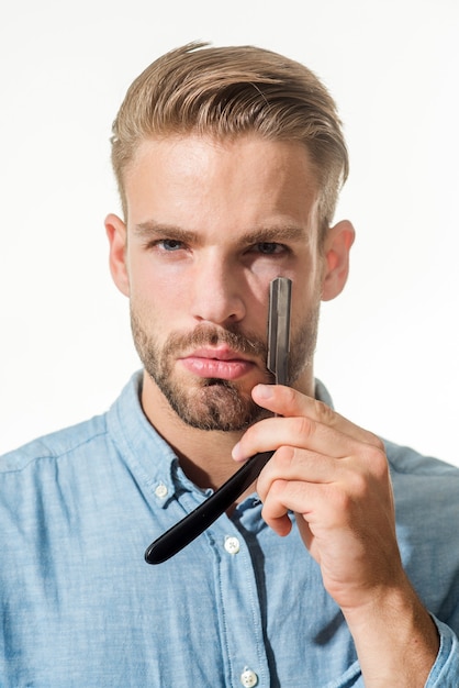 L'homme de barbier avec la barbe et la moustache tient le coiffeur de rasoir droit démontrant du salon de coiffure