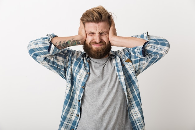 Homme barbu agacé vêtu d'une chemise à carreaux debout isolé, c