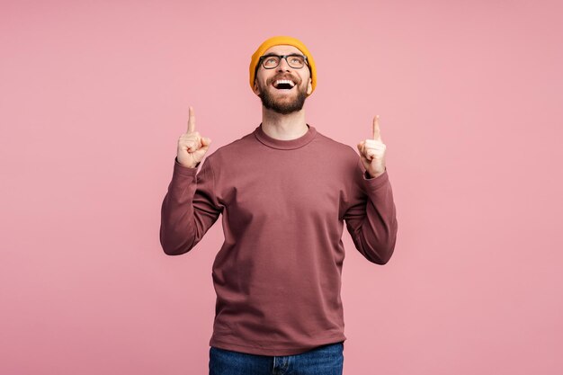 Un homme barbu d'âge moyen étonné, d'une quarantaine d'années, avec des lunettes et un chapeau jaune, pointant son index vers le haut.