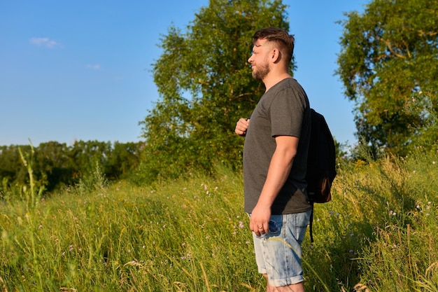 Homme barbu d'âge moyen avec un sac à dos lors d'une randonnée en regardant l'horizon