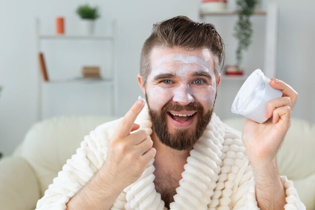 Homme barbu appliquant une crème antirides sur son visage, soins de la peau et concept de spa pour homme