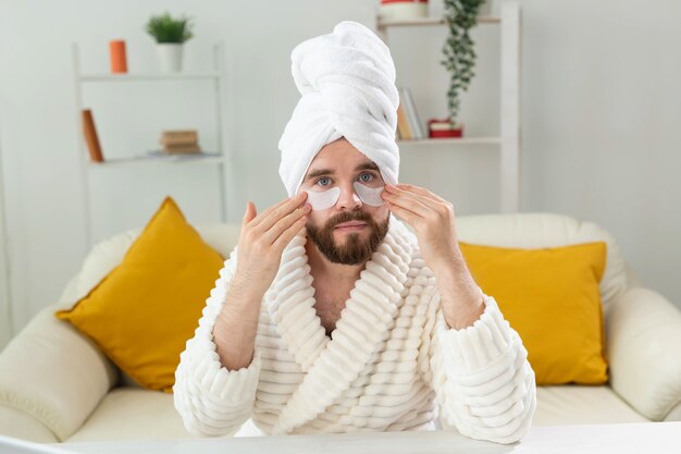 Homme barbu appliquant des patchs oculaires sur ses rides du visage et soins du visage à domicile pour hommes