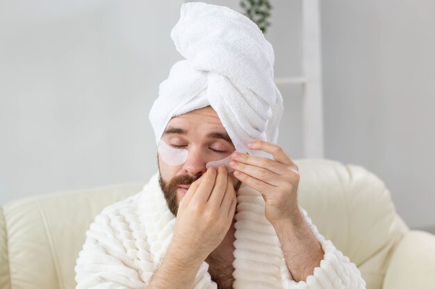 Homme barbu appliquant des patchs oculaires sur ses rides du visage et soins du visage à domicile pour hommes