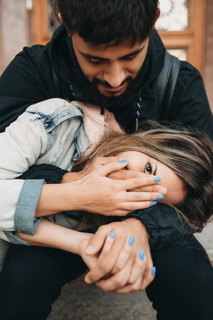 Homme barbu assis sur les marches en étreinte avec jeune femme s'amusant et étant amoureux