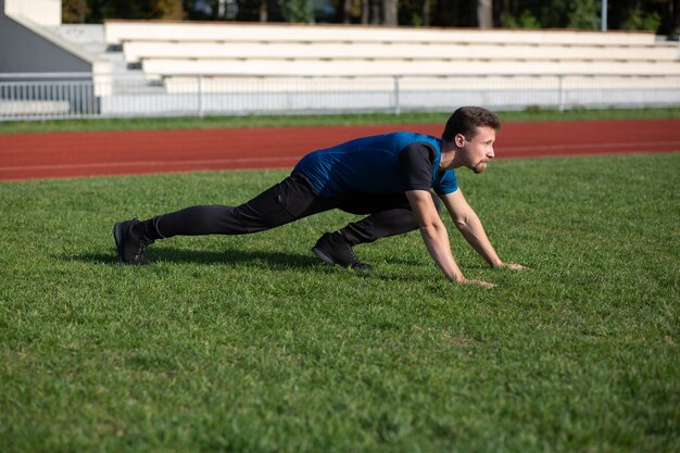 Homme barbu athlétique faisant des étirements des jambes avant de courir au stade. Espace libre