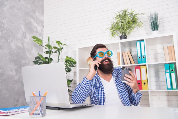 Photo un homme barbu au look brutal porte des lunettes cool dans un style décontracté parlant sur un téléphone portable dans un style moderne