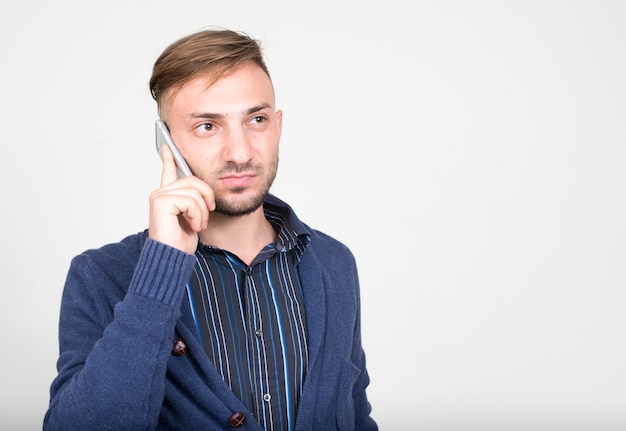 Homme barbu aux cheveux blonds contre un mur blanc